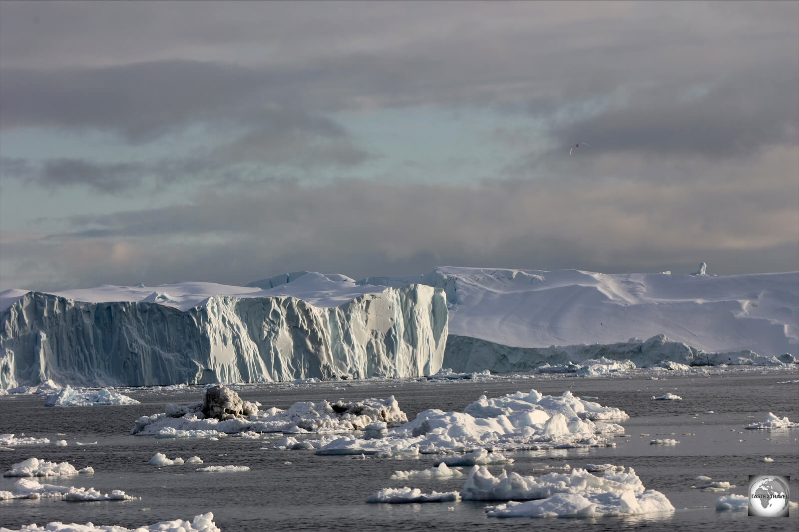 Floating icebergs the size of mountains slowly move into the sea from the Ilulissat Ice Fjord.