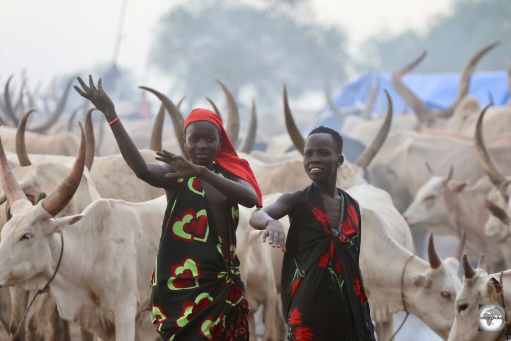 Young Mundari girls, imitating the curved horns of their cows.