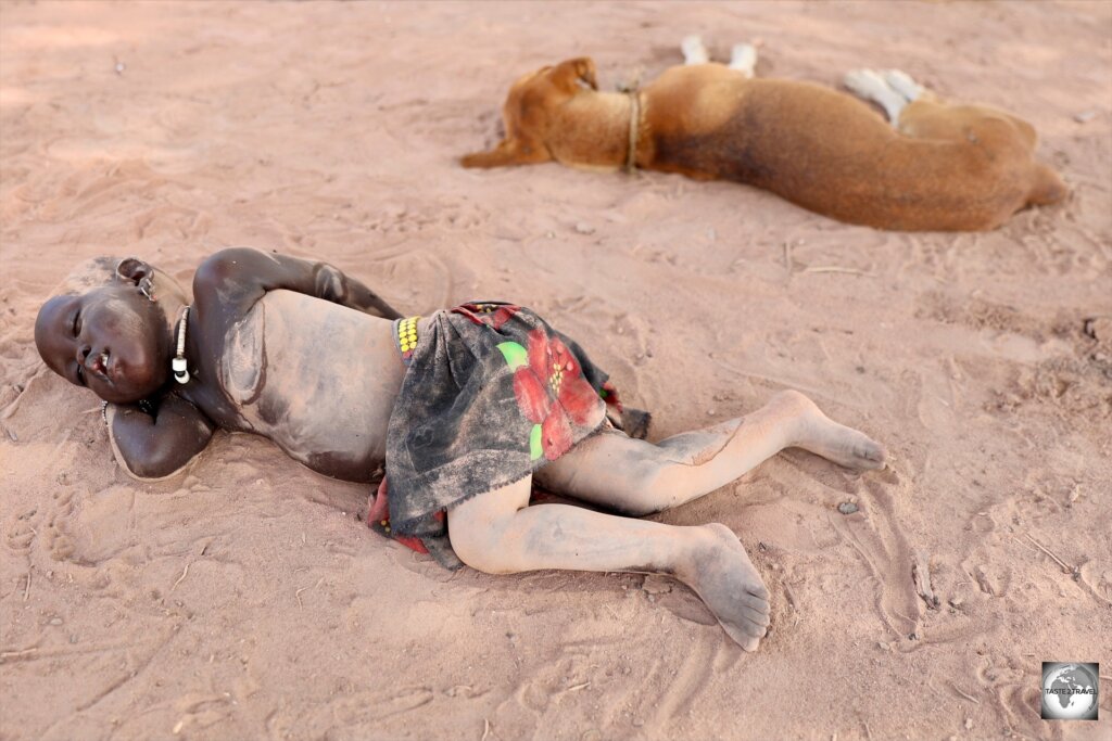 A Mundari baby, covered in cow-dung ash to protect against mosquito bites, sleeping on the ground.