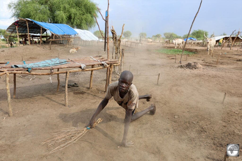 A Mundari boy, sweeping the camp grounds.