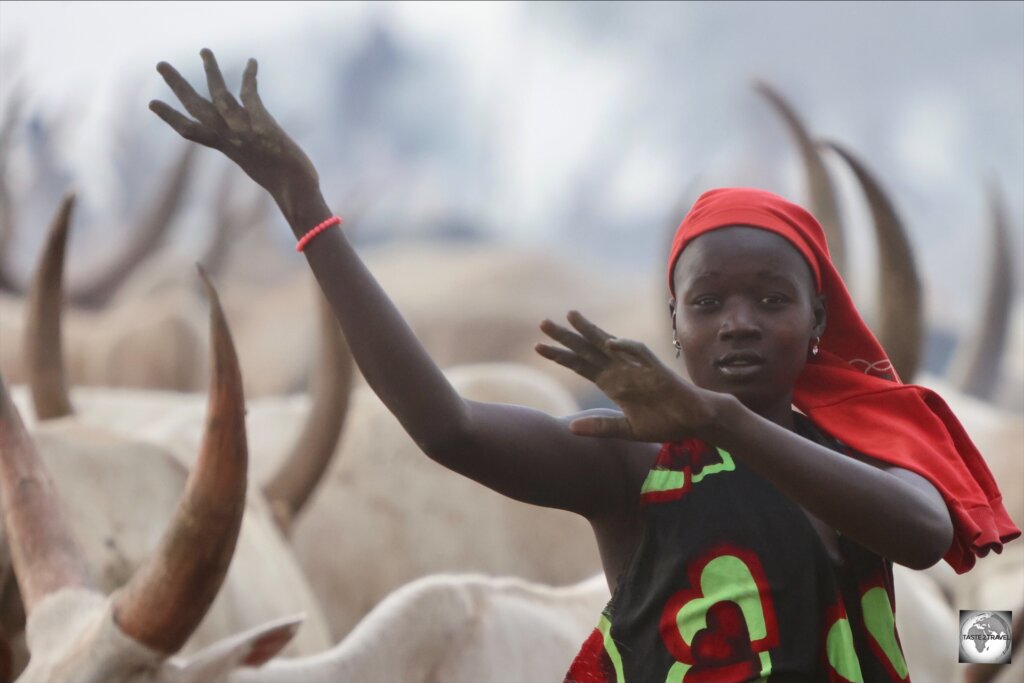 A Mundari girl using her arms to imitate the curvy cow horns.